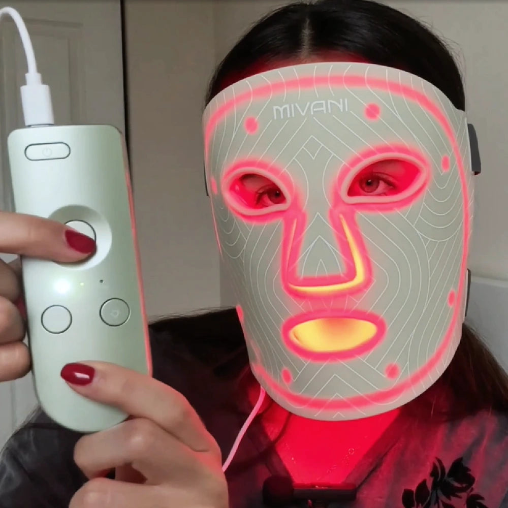 Person wearing a LED face mask with a control device, brand 'MIVANI' visible.
