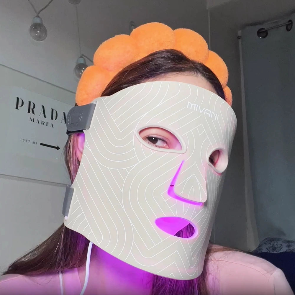 Person wearing a LED face mask with visible branding indoors.