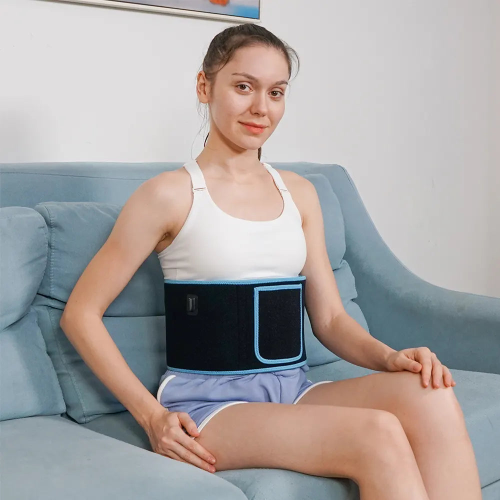 Woman wearing a black waist support belt sitting on a blue couch.