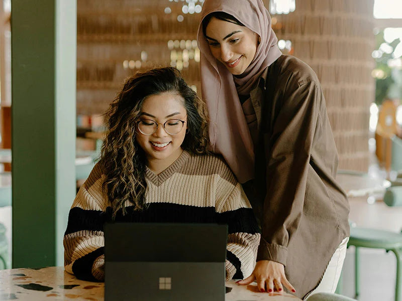 Two women looking at a laptop together in a casual setting