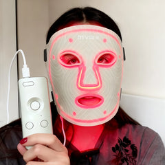 Person wearing a LED face mask with a remote control, branded 'MIVANI'.