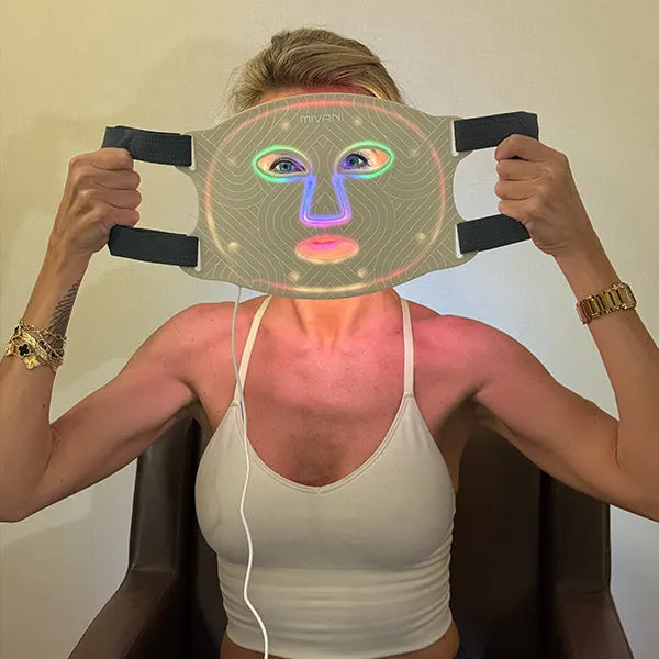 Person holding a therapy face mask with colorful design against a neutral background
